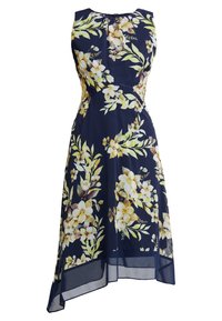 Bloemig jurkje met een marineblauwe achtergrond en gele en witte bloemen, zonder mouwen, met een asymmetrische zoom en doorschijnende afwerking.