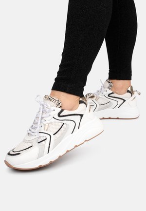 Sneakers bianchi in rete con accenti neri e un dettaglio sul tallone in oro texturizzato. Presentano un laccio prominente e una suola in gomma.