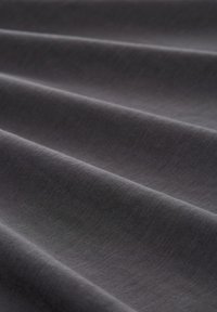 Tissu gris foncé avec une texture lisse, présentant des plis pliés qui créent une apparence ondulée et un éclat subtil.