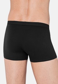 Boxer brief in cotone nero con un morbido elastico che presenta il nome del marchio. Tessuto liscio, design aderente e senza motivi visibili.