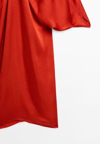 Czerwona satynowa tkanina o gładkiej teksturze, z luźnym, drapowanym fasonem i szerokimi rękawami, tworząc obfitą sylwetkę.