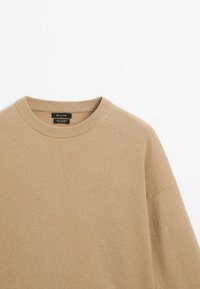 Pull en cachemire beige à col rond avec col côtelé, présenté à plat sur fond blanc.