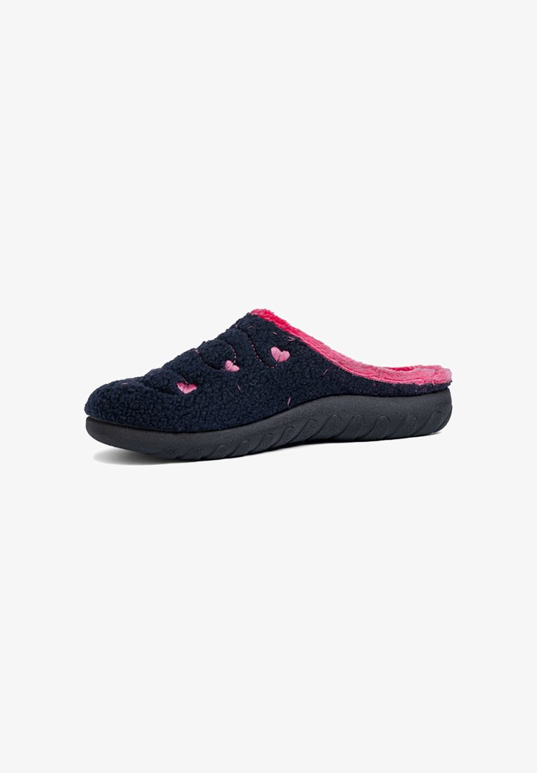 Pantofole in peluche blu navy con foderato in pelliccia rosa, fori a forma di cuore e suola in gomma nera testurizzata. Design strutturato a slip-on per il massimo comfort.