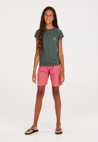 Groen rash guard met korte mouwen en zonafbeelding, gecombineerd met roze shorts met een ruitpatroon, gedragen met zwarte slippers, op een effen achtergrond.
