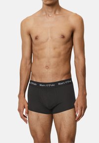Schwarze Baumwollboxershorts mit einem breiten Bund, der mit weißem "Marc O’Polo"-Branding versehen ist. Glatte Textur, taillierte Passform und Oberschenkel-lange Länge.