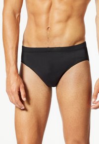 Slip da uomo neri realizzati in tessuto elastico e morbido. Presentano un ampio elastico in vita e un design senza cuciture per comfort e vestibilità.