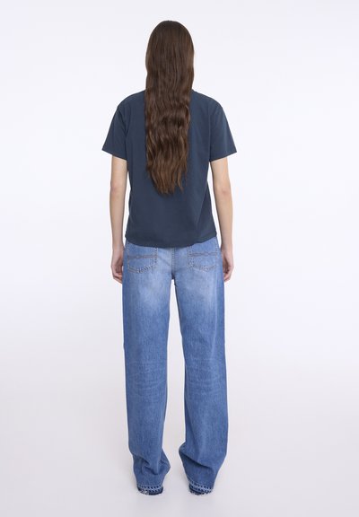 Námořnické modré tričko s krátkým rukávem a světle modré široké džíny. Měkká tkanina, volný střih a detaily zadní kapsy na džínech.
