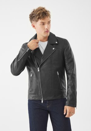 Zwarte leren motorjack met asymmetrische rits aan de voorkant, gezandstraalde kraag en ritszakken. Glad textuur met zilverkleurige accenten.