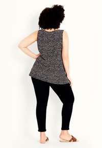 Schwarze ärmellose Tunika mit einem mehrfarbigen Blumenmuster, kombiniert mit dunklen Skinny Jeans und braunen Rutsch-Sandalen. Verfügt über einen lockeren Schnitt und einen abgerundeten Saum.