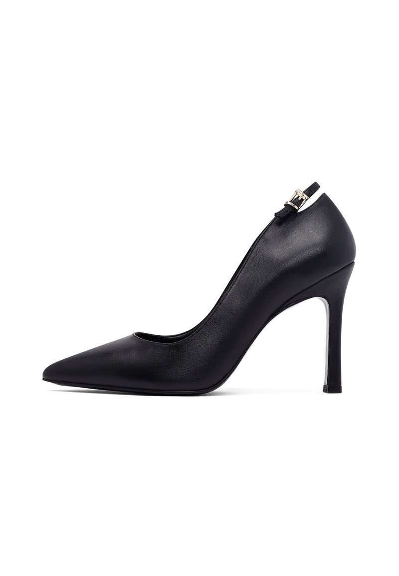 Zapatos de tacón alto de punta afilada en cuero negro con tiras al tobillo y hebilla dorada, diseño elegante y sofisticado, aislados sobre fondo blanco.