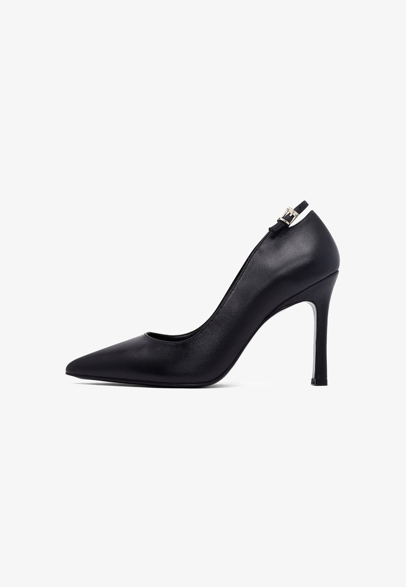 Zwarte leren high heel pumps met spitse neus, enkelbandje en gouden gesp, slank en elegant ontwerp, geïsoleerd op een witte achtergrond.