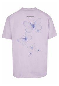 Lys lilla t-skjorte med et design av gjennomsiktige blå sommerfugler trykket på ryggen, med klassisk rund hals og korte ermer.