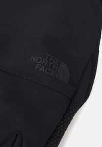 Gants noirs en tissu doux et extensible avec une texture antidérapante sur la paume. Présentent un logo noir en relief de "The North Face".