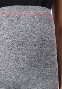 Leggings atletici grigi con una superficie testurizzata, caratterizzati da una cucitura accentuata rosa in vita e un design aderente.