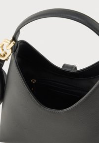 Čierna kožená kabelka so zlatým kovaním, zakriveným dizajnom, textúrovaným povrchom a vnútorným vreckom na zips. Priestranný a funkčný tvar.