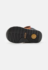 Pantofii multicolori prezintă o talpă din cauciuc texturat cu caneluri orizontale, accente din suede și un detaliu cu logo circular.