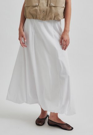Gonnona bianca lunga realizzata in tessuto leggero, con una silhouette fluida. Abbinala a ballerine in rete nere e a un gilet corto beige.