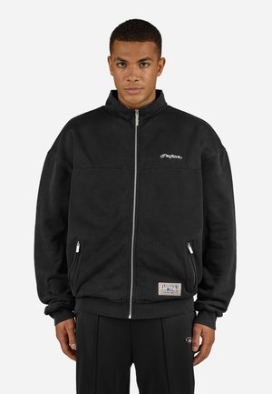 Black zip-up sweatshirt with a high collar, featuring side pockets and embroidered logo on the chest; made of soft, textured fabric.