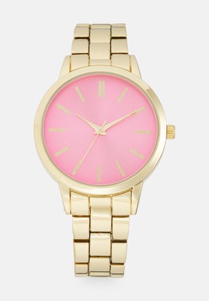 Montre-bracelet en métal doré avec un cadran rose, des index dorés et trois aiguilles dorées indiquant 10:10:36.