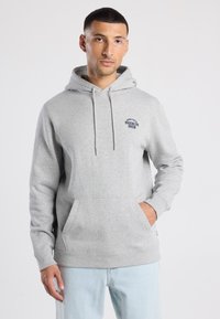 Felpa grigia realizzata in tessuto morbido, dotata di una tasca frontale e di un logo ricamato "Brooklyn Brew" sul lato sinistro del petto. Vestibilità rilassata.