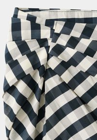Tissu à carreaux noir et blanc plié en un motif géométrique complexe et superposé.