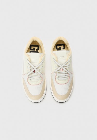 Scarpe sportive bianche e beige con tessuto a rete, dettagli testurizzati, punta rotonda e cuciture a contrasto. I lacci sono grigi, con il marchio sulla linguetta.