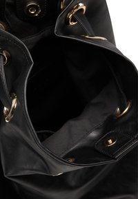 Svart läder tote-väska med guldfärgad hardware, som har ett rymligt inre och justerbara sidodetaljer. Slät textur med en enkel design.