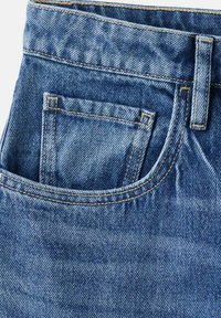 Jeans in denim blu con una tasca frontale decorata da cuciture e una cintura visibile. Il tessuto presenta un classico motivo e trama a spina di pesce.