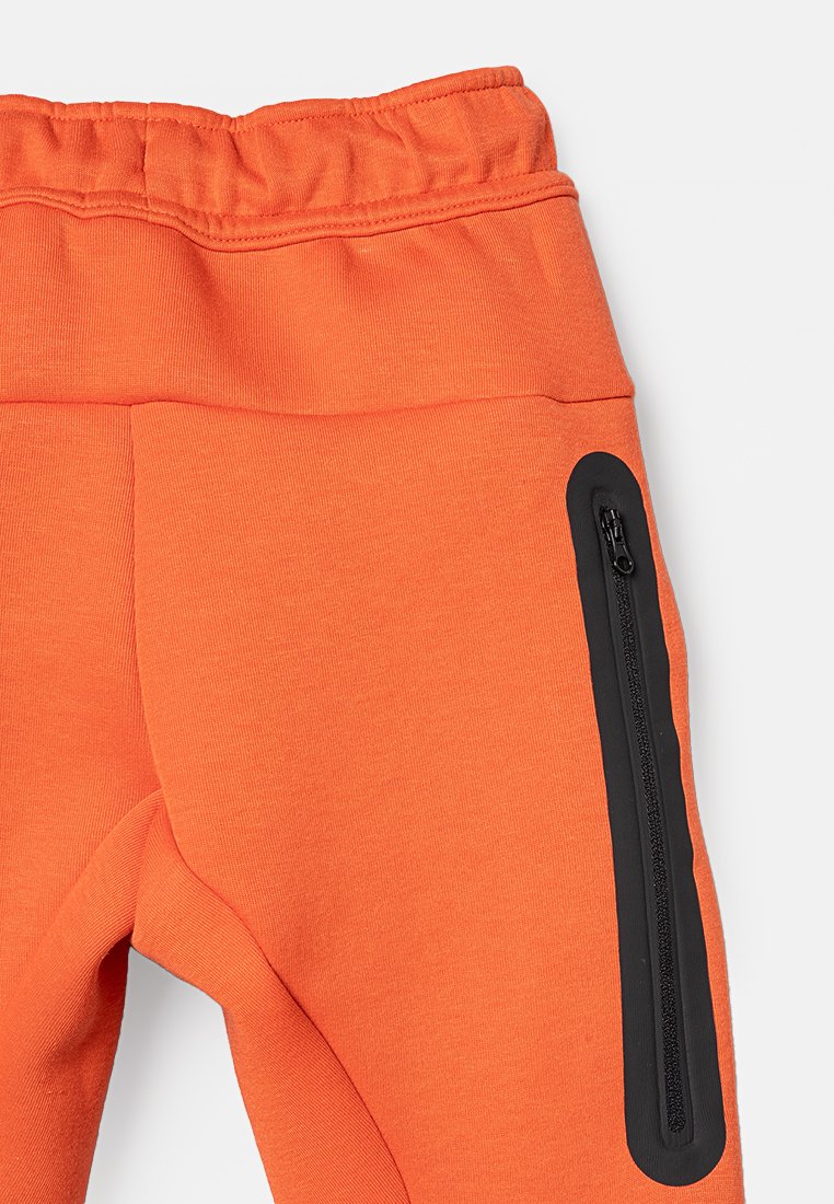 Oranger Stretchstoff-Hosen mit einer schwarzen, mit Reißverschluss versehenen Seitentasche und einem elastischen Bund, entworfen für Komfort und Funktionalität.