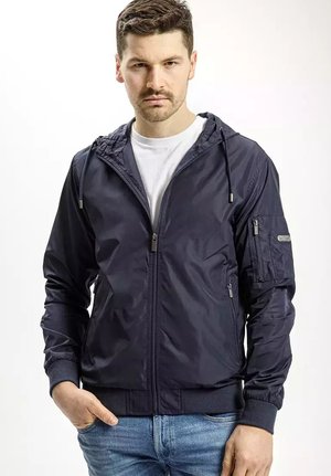 Granatowa kurtka zapinana na zamek, wykonana z lekkiego materiału, z kapturem, ściągaczami na rękawach oraz kieszenią na zamek na klatce piersiowej. Gładka tekstura z praktycznym designem.