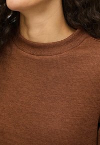 Maglione marrone lavorato a maglia con scollo a costine e trama liscia, con primo piano del tessuto e dell'area del collo.