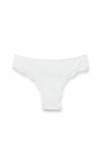 Bílá krajková tanga s vroubkovanými okraji. Materiál má měkkou, jemnou texturu a zdobí je složité květinové vzory po celé ploše.