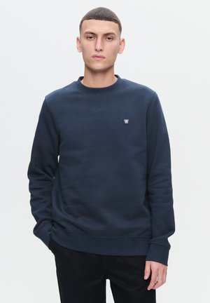Navy blue sweatshirt with crew neckline, ribbed cuffs, and waistband. Features a small logo on the chest. Smooth cotton fabric.