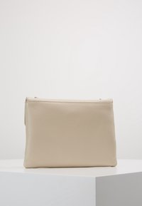 Beige nahkakotelo, jossa on teksturoitu pinta, suorakulmainen muoto, ylhäältä avattava vetoketju ja minimalistinen muotoilu. Sileä pinta, ei näkyvää metalliosaa.