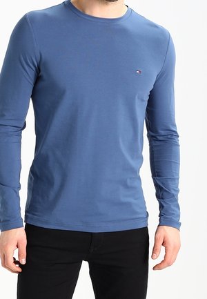 Camicia a maniche lunghe blu in morbido misto cotone con scollo rotondo. Piccolo dettaglio logo sul petto, design aderente, texture liscia e tessuto elasticizzato.