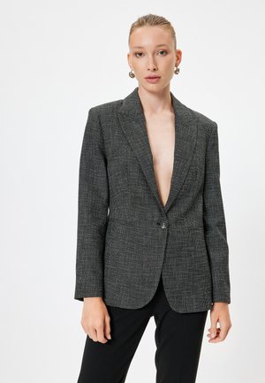 Grijze textuur blazer met een enkele knop, notch revers en twee voorzakken. Draagt over zwarte broeken met een getailleerde pasvorm.