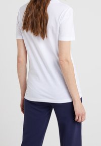Witte katoenen T-shirt met korte mouwen, een ronde halslijn en een gladde textuur, gecombineerd met marineblauwe ribbroek.