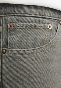Sivi denimski bokserji z zadnjim žepom, okrašenim s kapkovnimi zakovicami in vidnim teksturiranim vzorcem tkanine. Detajli šivanja ob robovih.