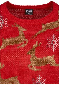 Pull rouge en maille avec un motif de renne en paillettes dorées et des flocons de neige blancs, étiquette Urban Classics visible au col, taille XS.