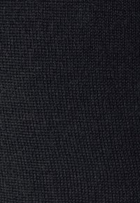 Gros plan sur un tissu noir étroitement tricoté avec un motif texturé subtil formant des lignes verticales.