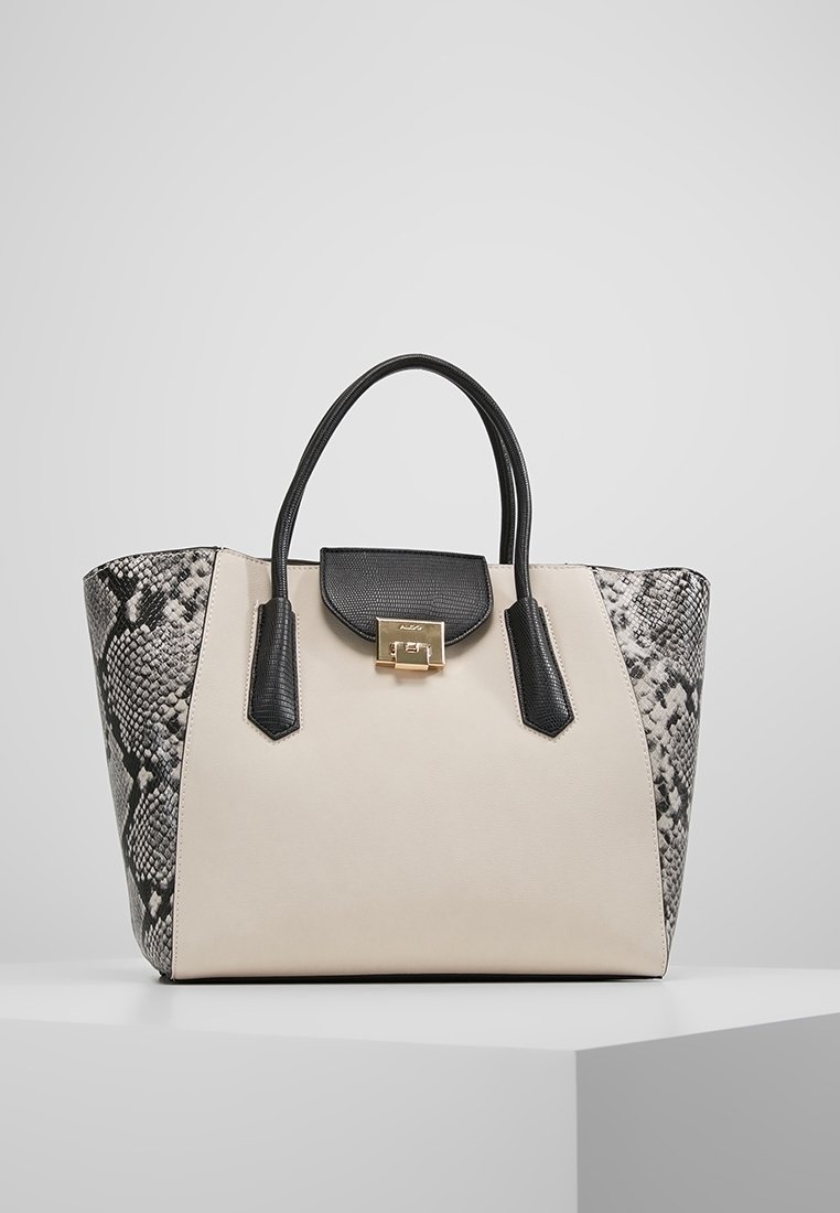 Beige och svart handväska med en slät framsida, texturerade ormskinnsmönstrade sidor och ett guldfärgat spänne. Två stadiga svarta handtag.