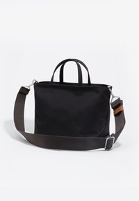 Czarna torba materiałowa na ramię z dwoma krótkimi uchwytami i odpinanym brązowym paskiem. Charakteryzuje się prostym designem z minimalnym przeszyciem.