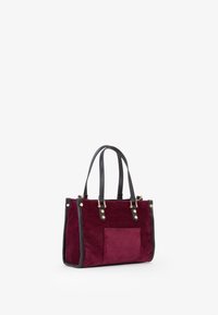 Borsa a spalla in suede bordeaux con rifiniture in pelle nera, due manici, dettagli in oro e una tasca frontale. Design geometrico e strutturato.