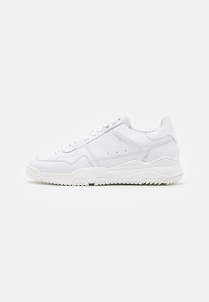 Bílé kožené tenisky s texturovanými detaily, zavazováním na tkaničky a gumovou podrážkou se vzorem v cikcak pro lepší přilnavost.