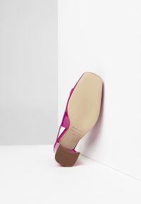 Scarpa con tacco alto in pelle verniciata rosa, con punta arrotondata e tacco robusto. Texture liscia, dettagli minimi e suola beige con motivo antiscivolo.