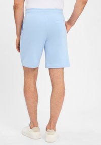 Light blue sweat shorts with a soft texture, elastic waistband, side pockets, and a rear pocket, ending above the knee.