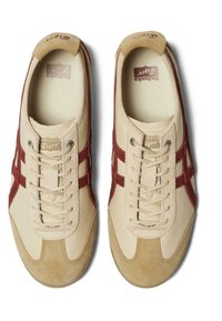 Béžové tenisky s červenými semišovými akcenty, texturovaná kůže na svršku, béžové tkaničky, polstrovaný límec a vložka s vzorem herringbone.