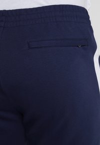 Marina sweatpants med ribbad midja, en diskret bakficka och en slät yta med en kontrasterande sidopaneldesign.