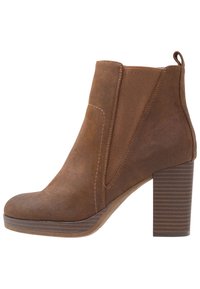 Brązowe zamszowe botki za kostkę z okrągłym noskiem, bocznymi elastycznymi panelami i żeberkowym obcasem. Gładka tekstura z kontrastującymi ściegami.