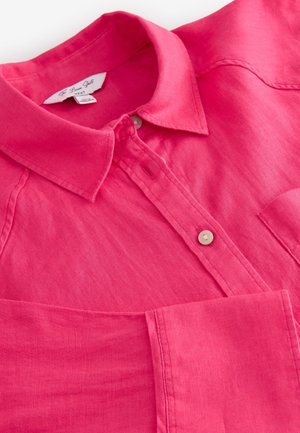 Pink linen shirt with a button-down collar, featuring a patch pocket and subtle texture. Includes a single button at the collar.